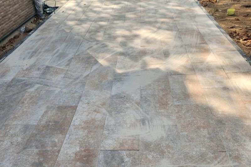 Große Terrassenfläche aus sandfarbenen Großformatplatten neben einer Hauswand